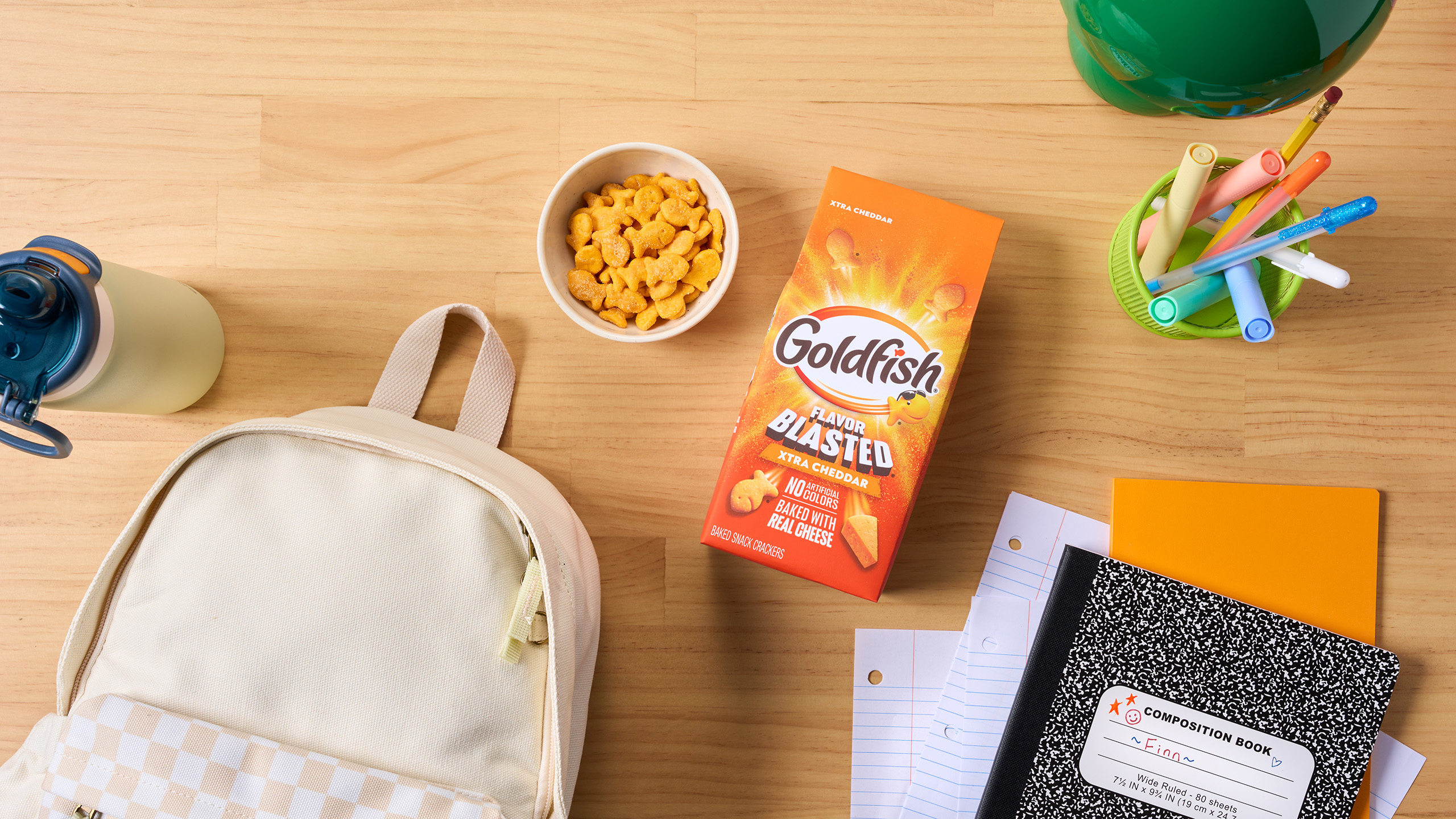 Goldfish Flavor Blasted crackers shown in an after-school snack setting with school supplies and a backpack.