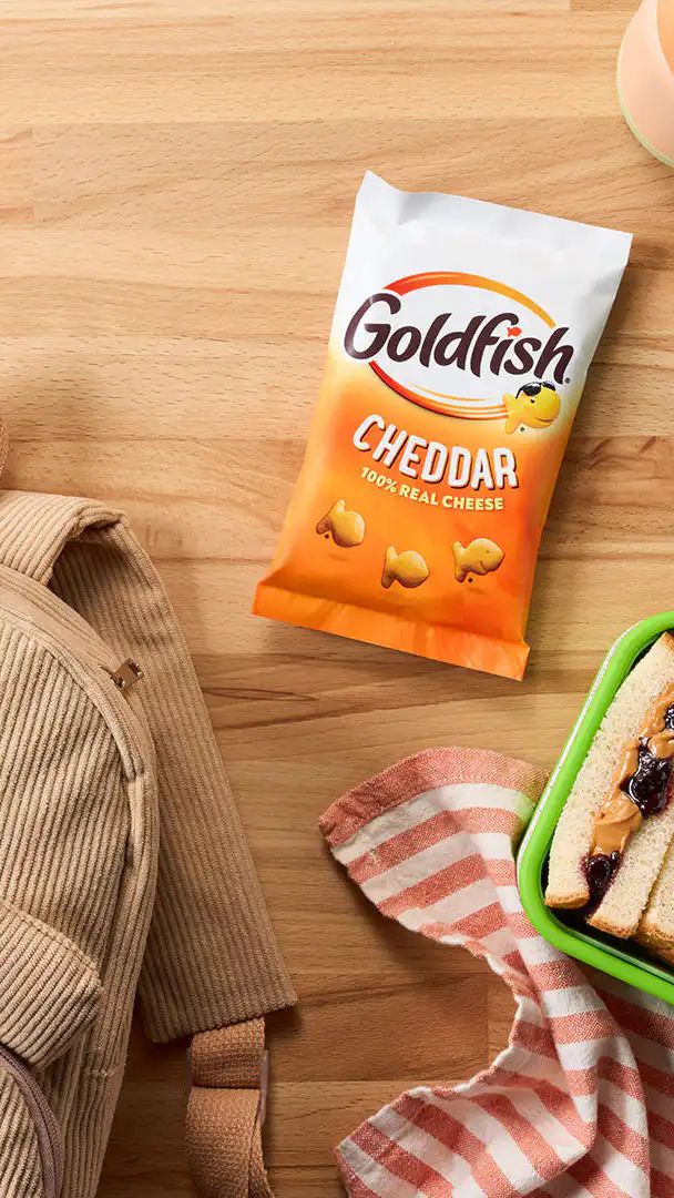 Goldfish Flavor Blasted Xtra Cheddar crackers with school supplies, a backpack, and a bowl of crackers.